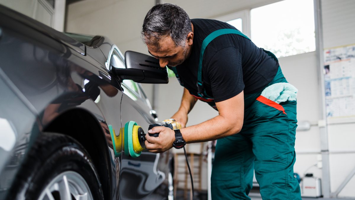 mechanic using an orbital polisher on car paint