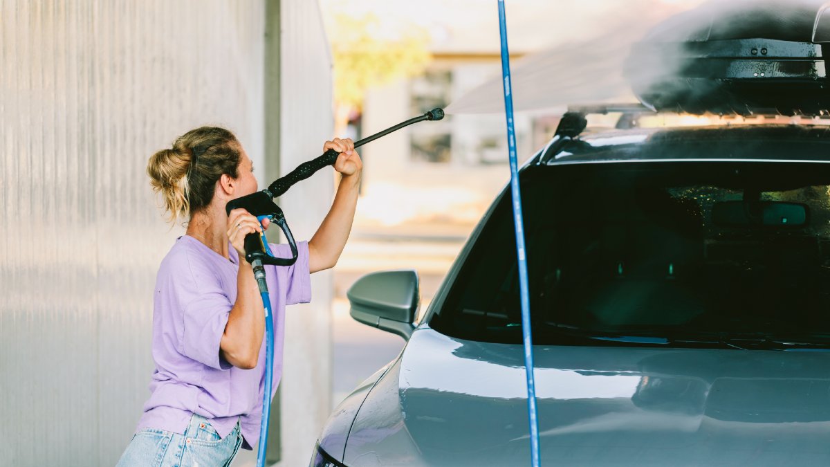 young woman cleaning her car including roof rack and cargo box