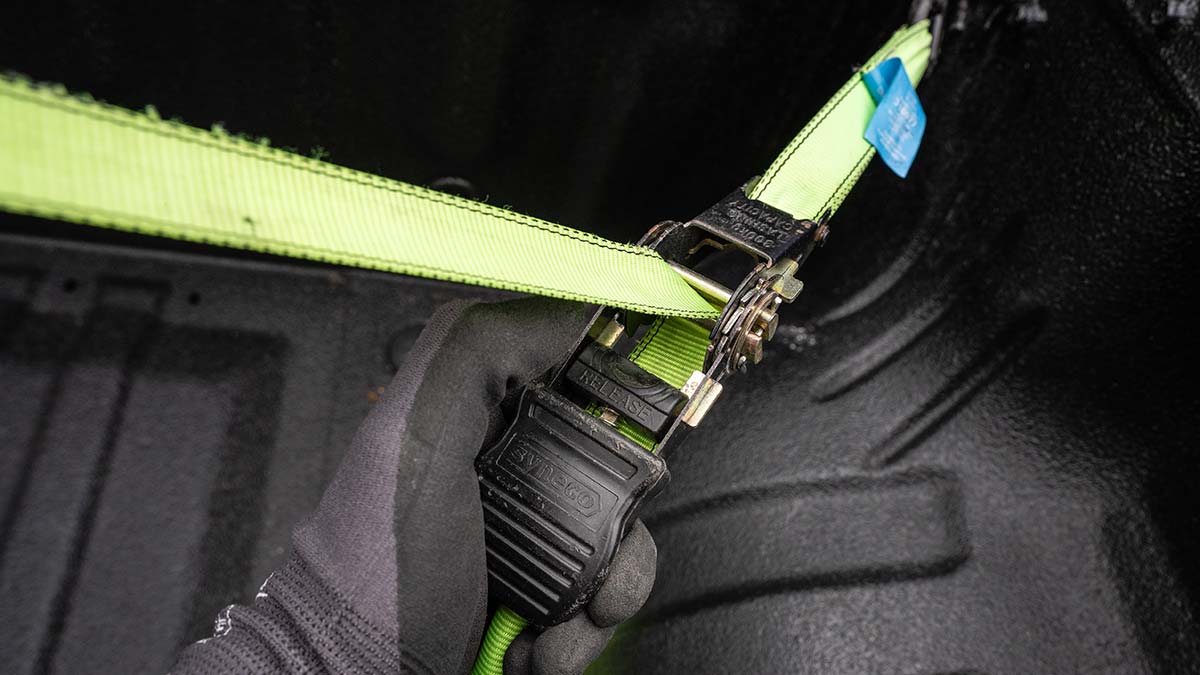 Close-up of strap being pulled tight through ratchet