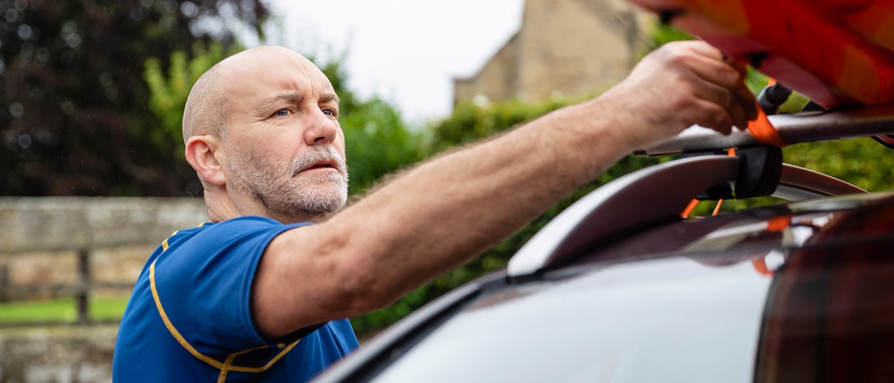 Man securing canoe to roof racks