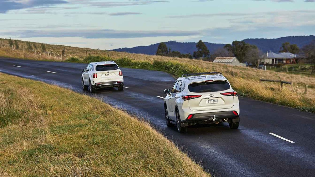 White Kia Sorento and white Toyota Kluger rear driving