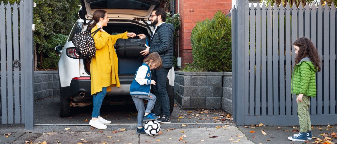 A woman, man and two small children with a soccer ball loading bags into a SUV 