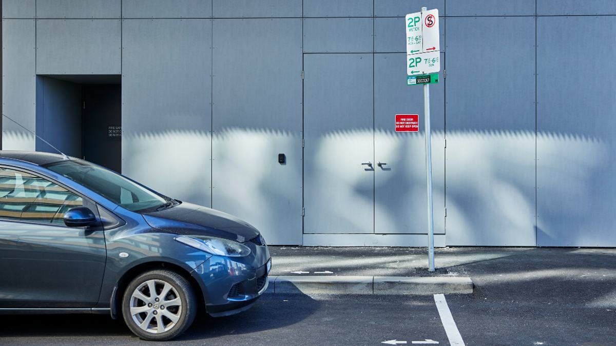 A car parked on the side of a road near a parking sign