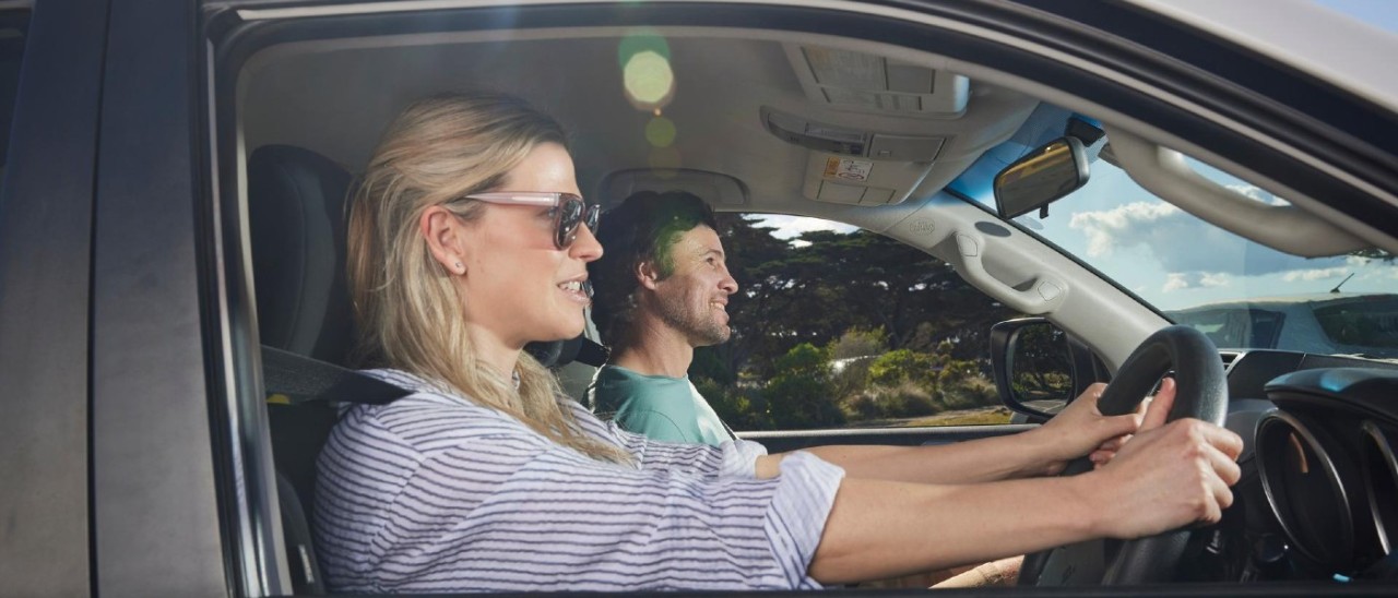 A woman driving a car while a man sits in the front passenger seat