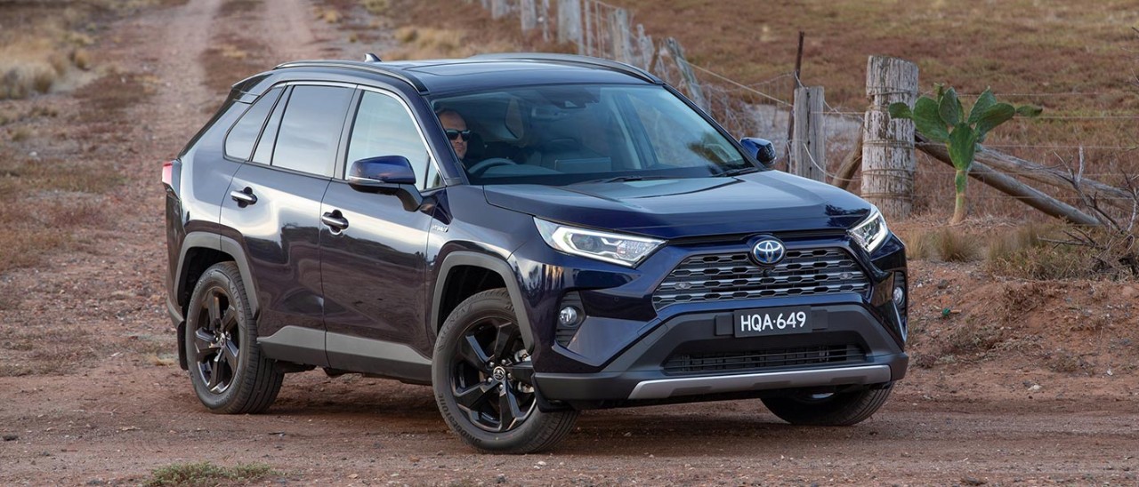 2021-Toyota-RAV4-Cruiser-Hybrid-banner-1400x600 Black Toyota RAV4 Hybrid turning left at dirt road intersection in rural area