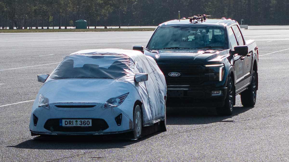 Large black Ford F-150 pick-up truck close behind much smaller white passenger car in ANCAP safety test.