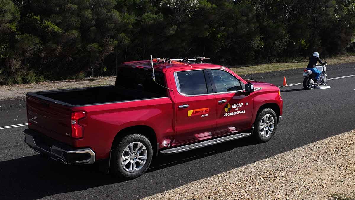 Large red Chevrolet Silverado pick-up truck close behind motorcycle dummy in ANCAP safety test.
