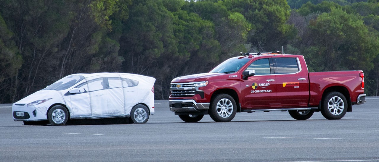 Large red Chevrolet Silverado pick-up truck close behind much smaller white passenger car in ANCAP safety test.