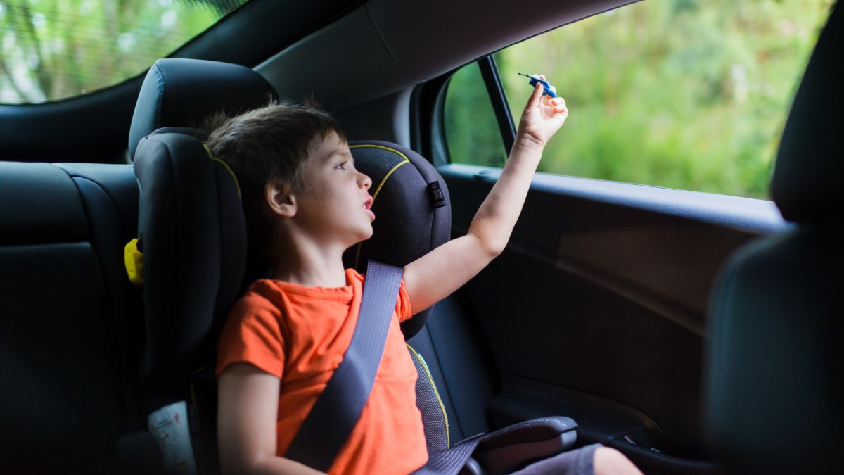 a young boy sitting in a booster seat and playing with a small toy