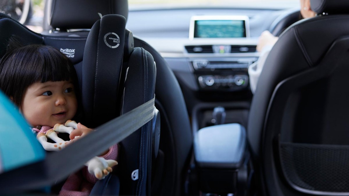 A baby in a child car seat with a giraffe teething toy