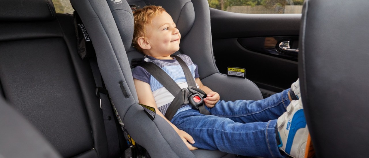 A toddler sitting in a forward-facing child car seat