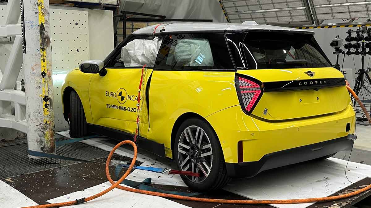 Yellow Mini Cooper E with airbags deployed and side panels dented after collision with pole in Euro NCAP testing.