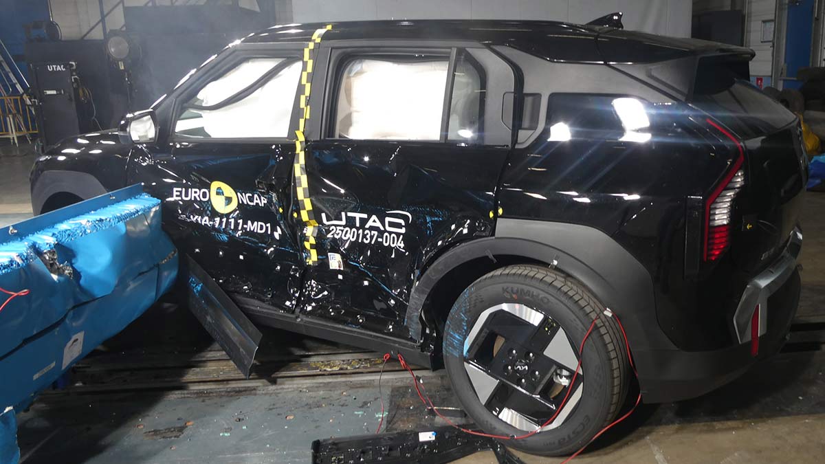 Black Kia EV3 small SUV with damaged side panels and barrier against front door after Euro NCAP crash test.