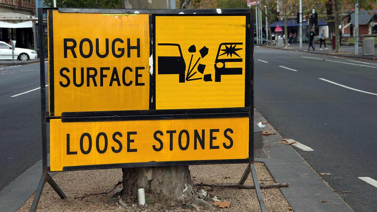 road sign warning of loose stones that may harm windscreens