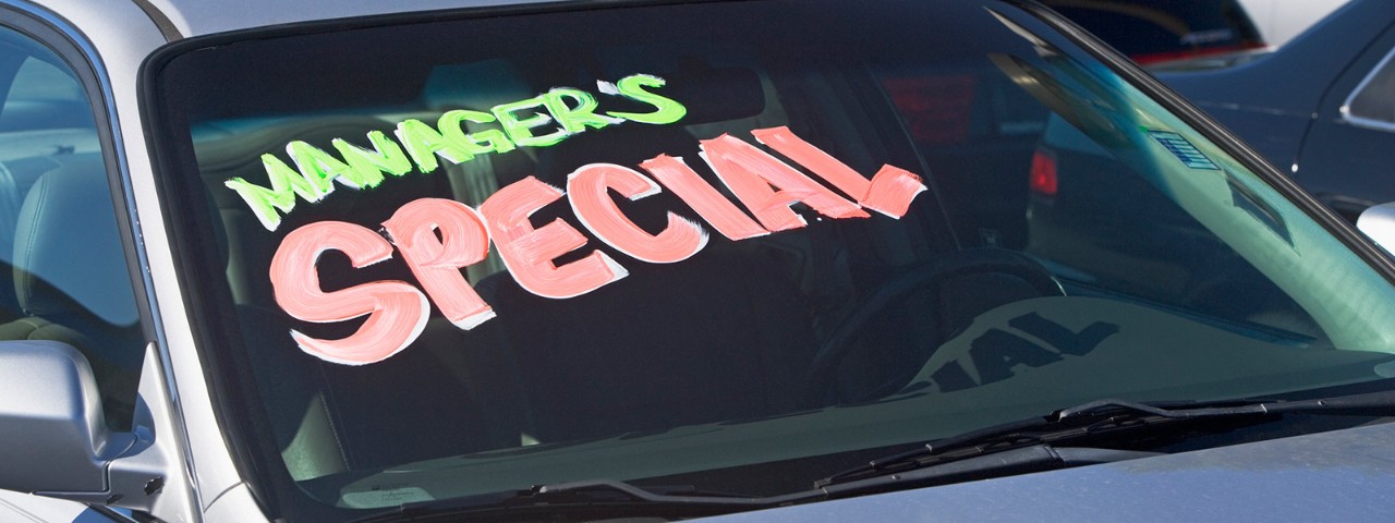 A car for sale with a fluro painted sign on the windscreen saying 'manager's special'