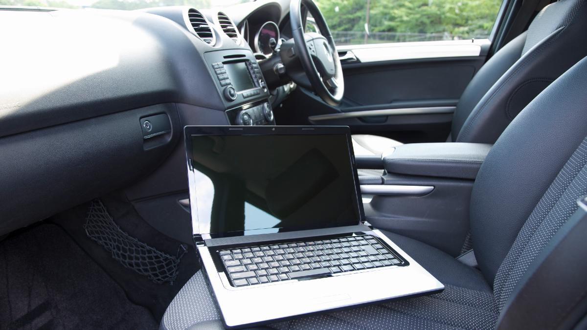 Laptop sitting on passenger seat in car.