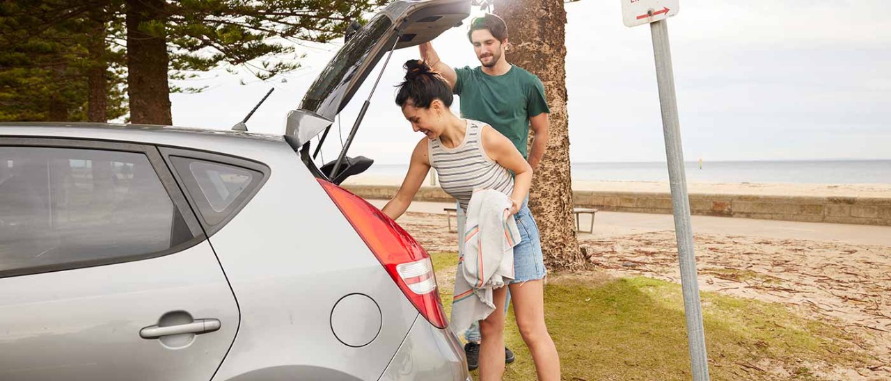 Couple getting belongings out of car at the beach.