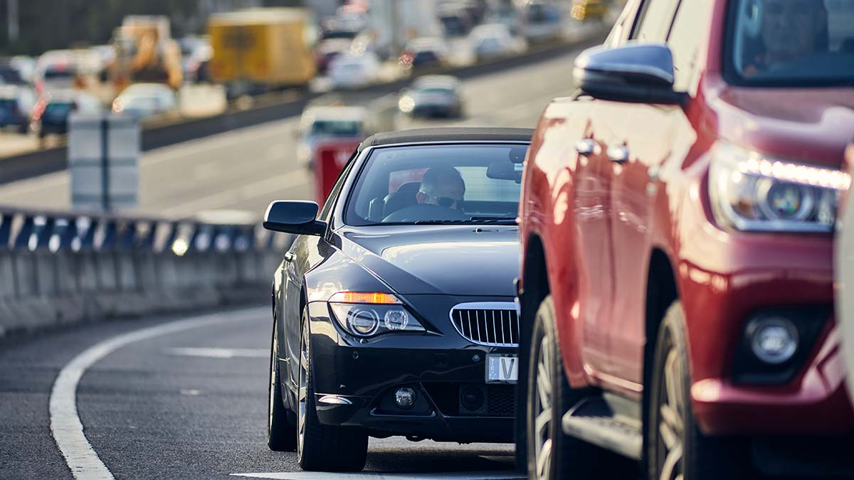 Close-up of two car driving on freeway with busy traffic in background.