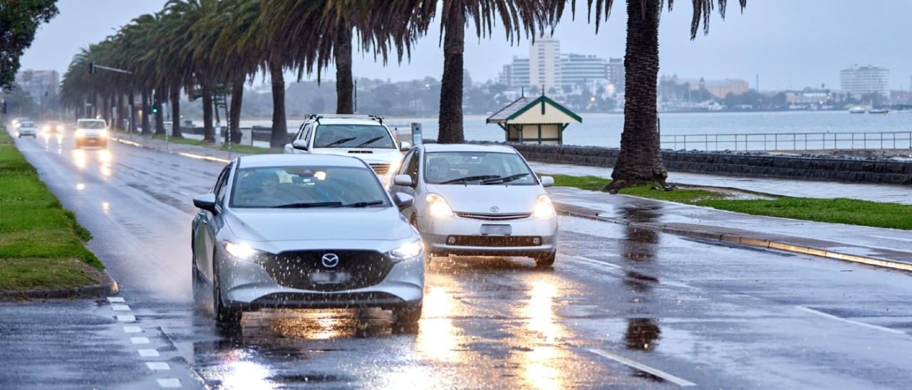 Cars driving along Beach Road in Melbourne on a dark and rainy afternoon. Cars driving along Beach Road in Melbourne on a dark and rainy afternoon. Each car has its headlights on.