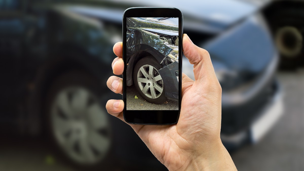 person taking photo of damaged car