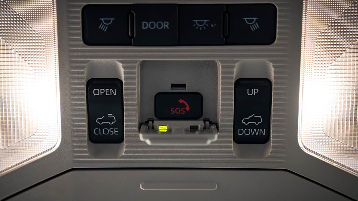 Overhead console of Toyota RAV4 Edge Hybrid showing SOS emergency call button and green indicator light next to other switchgear