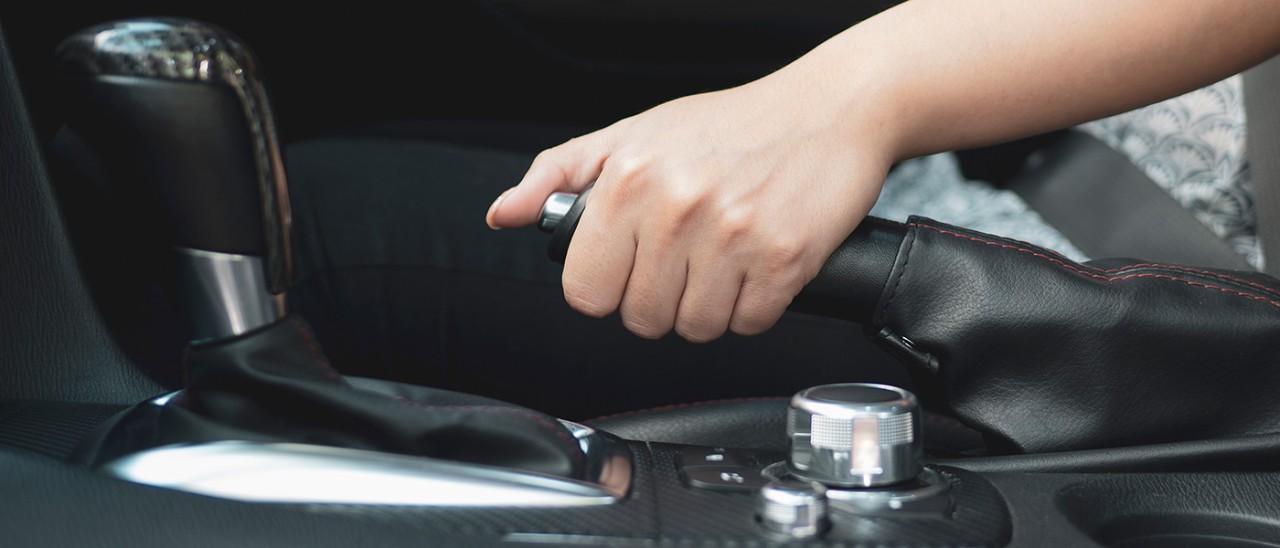 Hand pressing handbrake in car
