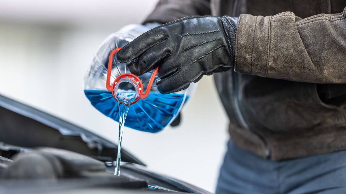 man pouring coolant into car engine