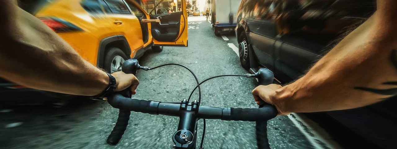 Cyclist holding onto handle bars riding fast down street.