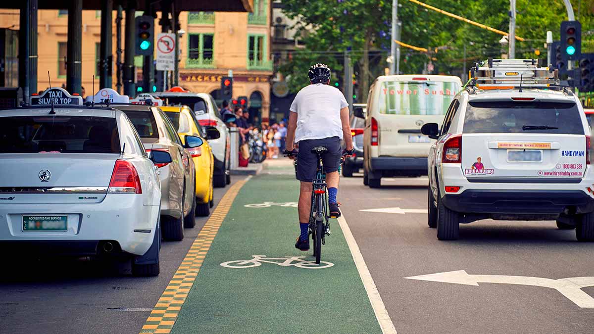 Rear view of cyclist and cars on St Kilda Road in Melbourne.