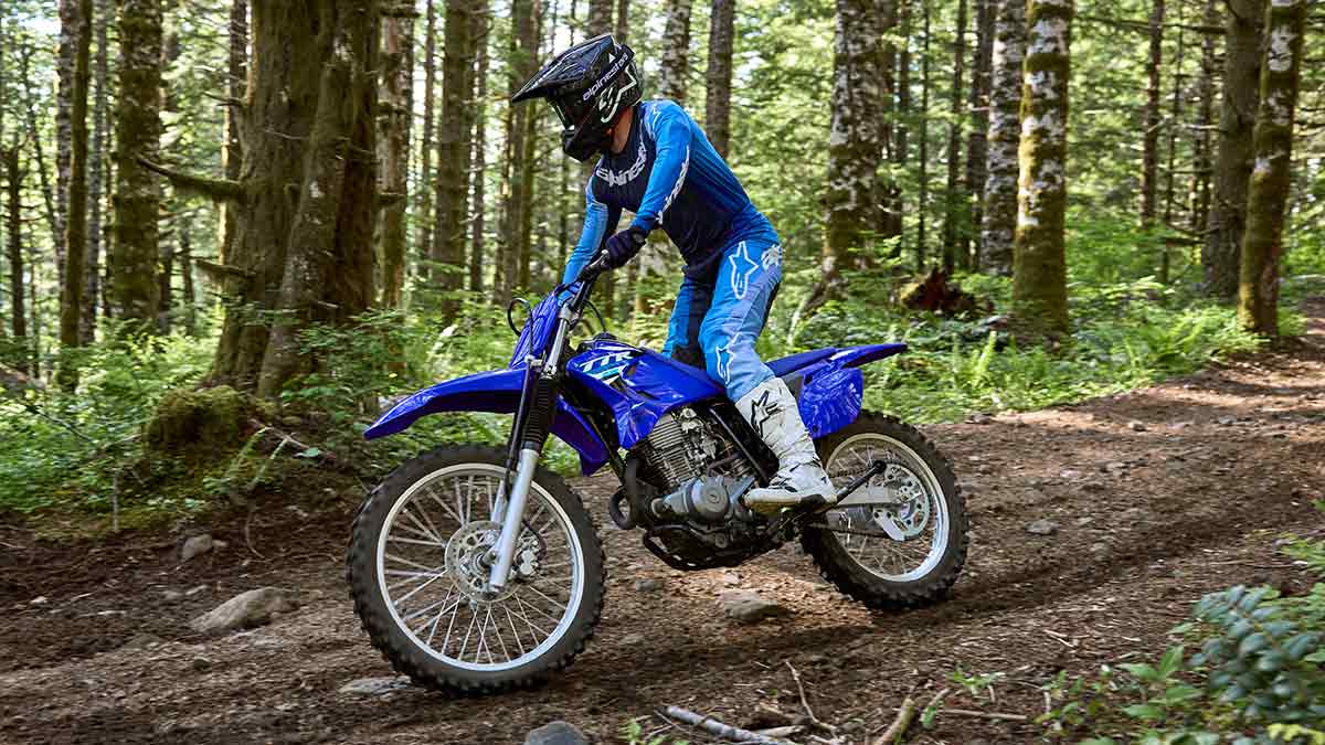 Yamaha trail bike rider navigating rocky track in forest