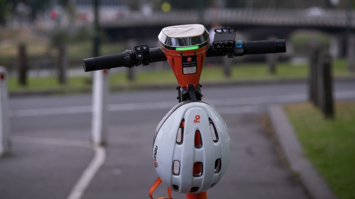 orange hire e-scooter with white helmet