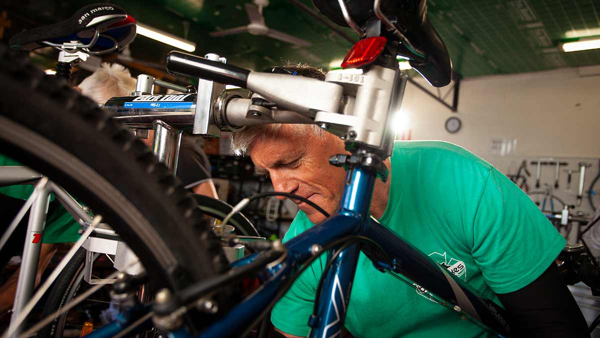 man in green shirt fixing bicycle chain