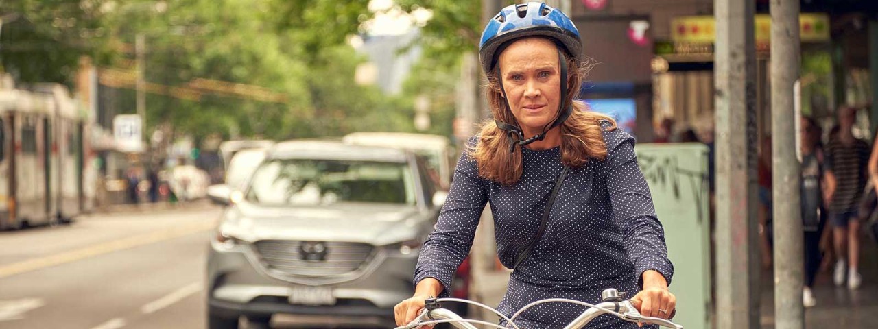 Woman in helmet riding bike down city street.