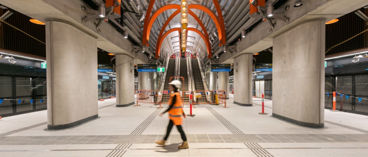 State Library Station A construction worker wearing an orange high vis vest walking on a platform at State Library Station