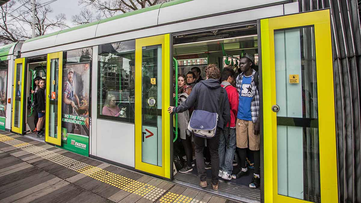 People packing into a tram with doors about to close.