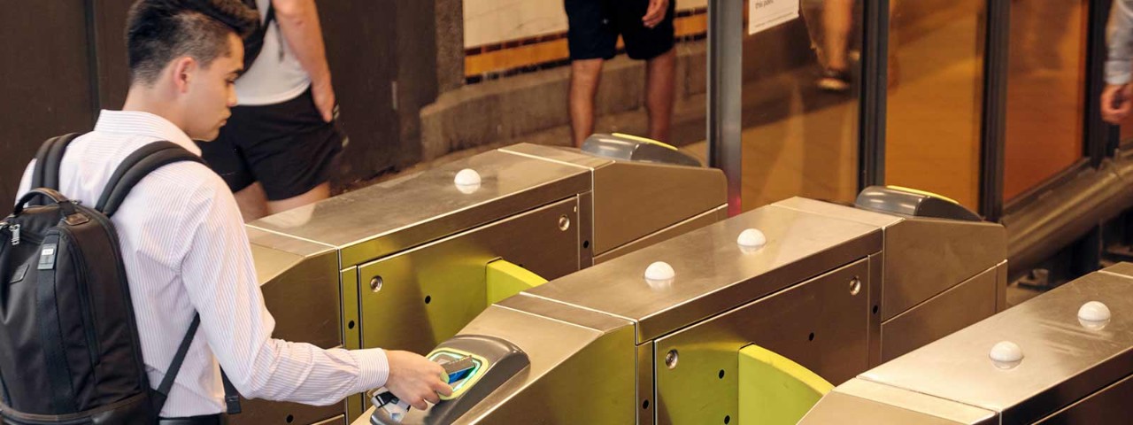 Man at train station touching on with Myki card.