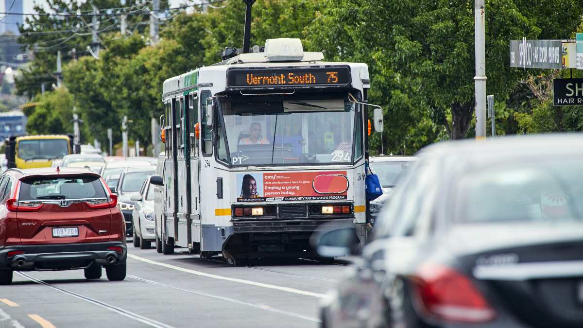 A route 75 tram travelling down a busy road in Melbourne