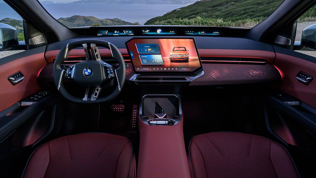 Left-hand-drive BMW iX3 interior with earthy brown Castanea trim, large central screen and panoramic display across lower windscreen.