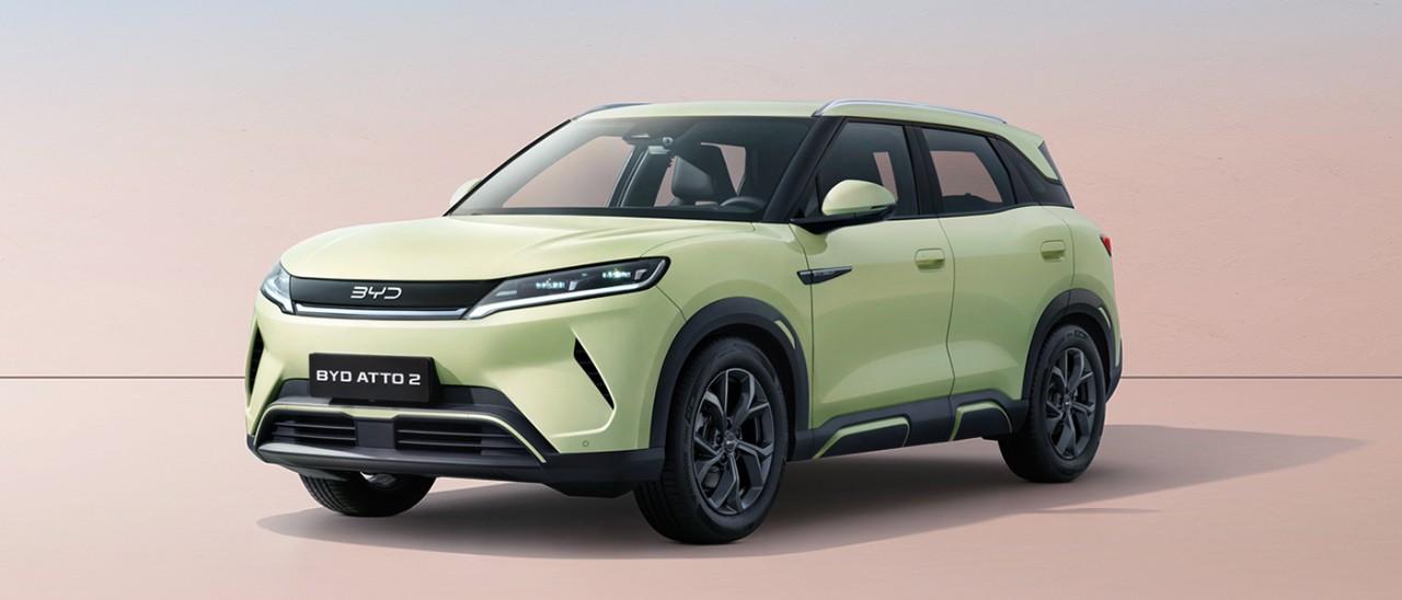 2026-BYD-Atto-2-front-static-banner-1400x600 Front quarter studio shot of light green BYD Atto 2 small electric SUV with pastel tan background