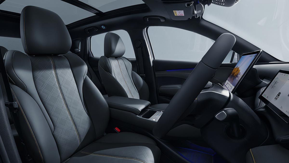 View from driver's door of BYD Atto 3 interior with grey synthetic leather seat trim and steering column-mounted gear shifter.