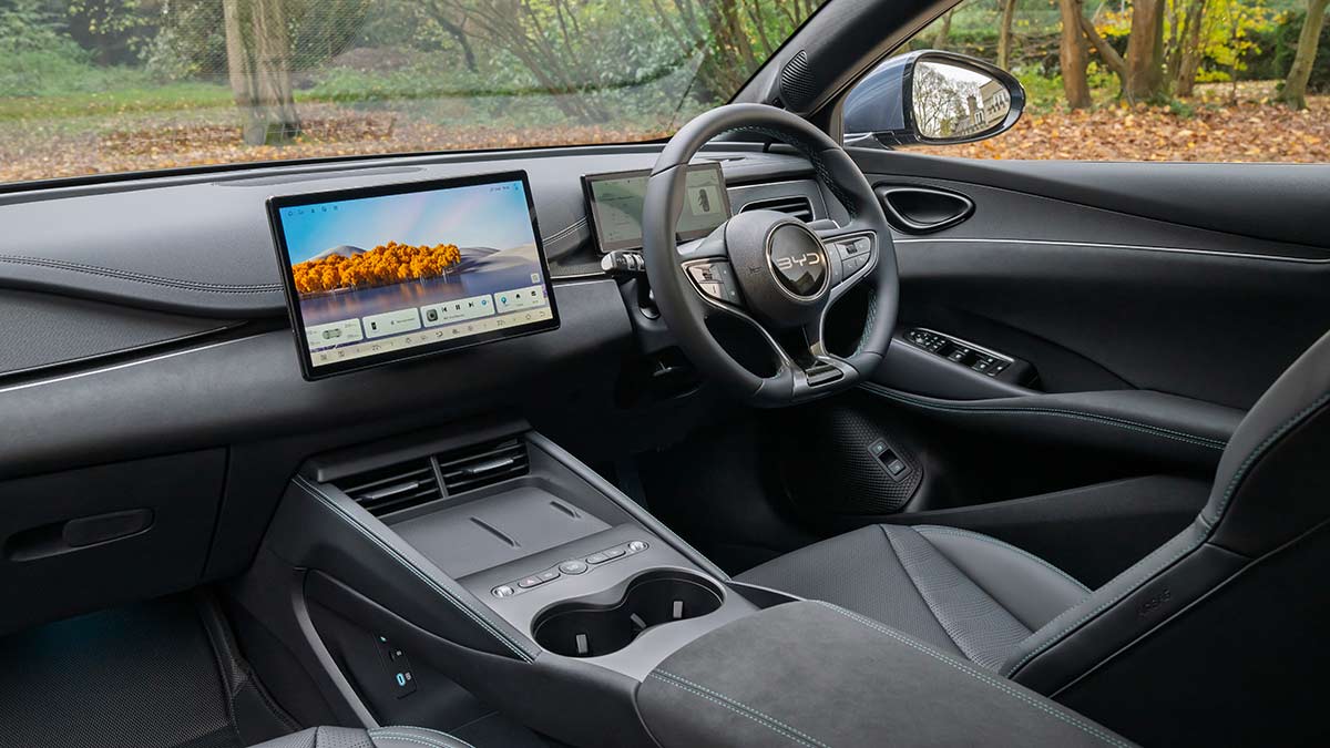 Dash area of UK-spec BYD Seal 6 Touring hybrid wagon with dark trim, twin digital screens and wireless charging pads.