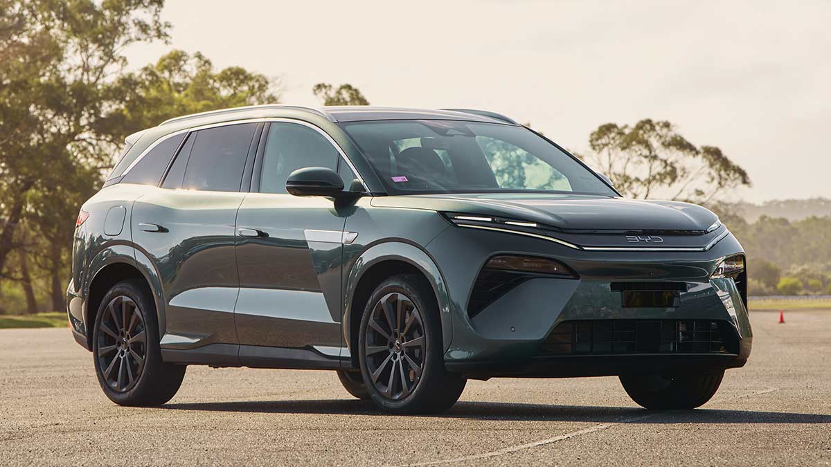 BYD Sealion 8 SUV in dark aquamarine metallic colour parked on forecourt in sunlight with gum trees behind at Lang Lang proving ground.