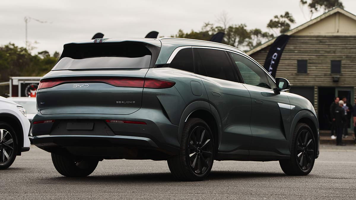 Rear three-quarter view of BYD Sealion 8 large SUV in dark aquamarine metallic colour parked in front of chalet and other cars at Lang Lang proving ground.
