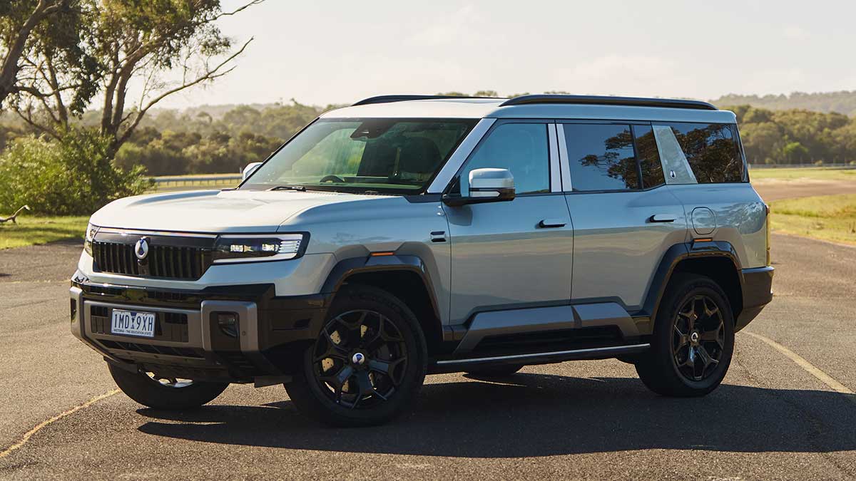 Light-coloured Denza B8 large luxury SUV parked on concourse at Lang Lang proving ground with gumtrees behind.