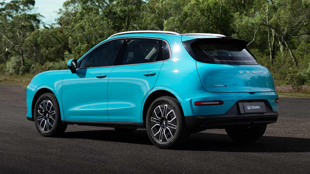 Rear shot of duck-egg blue GWM Ora 5 electric small SUV parked on forecourt in front of bushland at Lang Lang proving ground in Victoria.