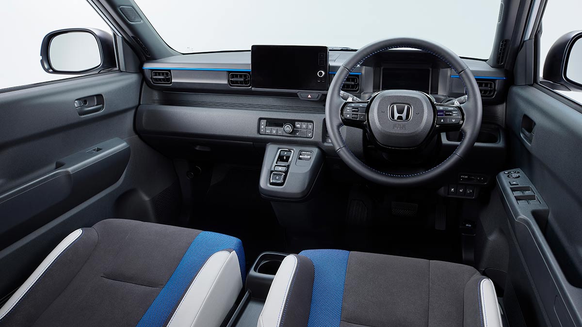 Cockpit of Honda Super-One EV with digital screens, lower dash controls and blue lighting and trim highlights.