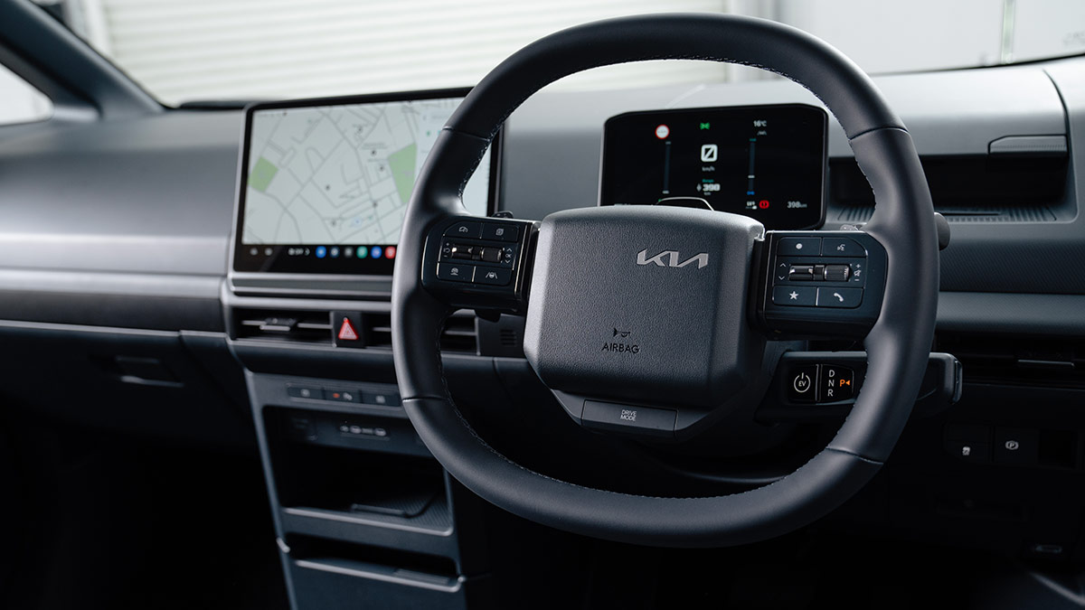 Kia PV5 Cargo close-up interior shot of multi-function steering wheel, digital driver's display and central touchscreen.
