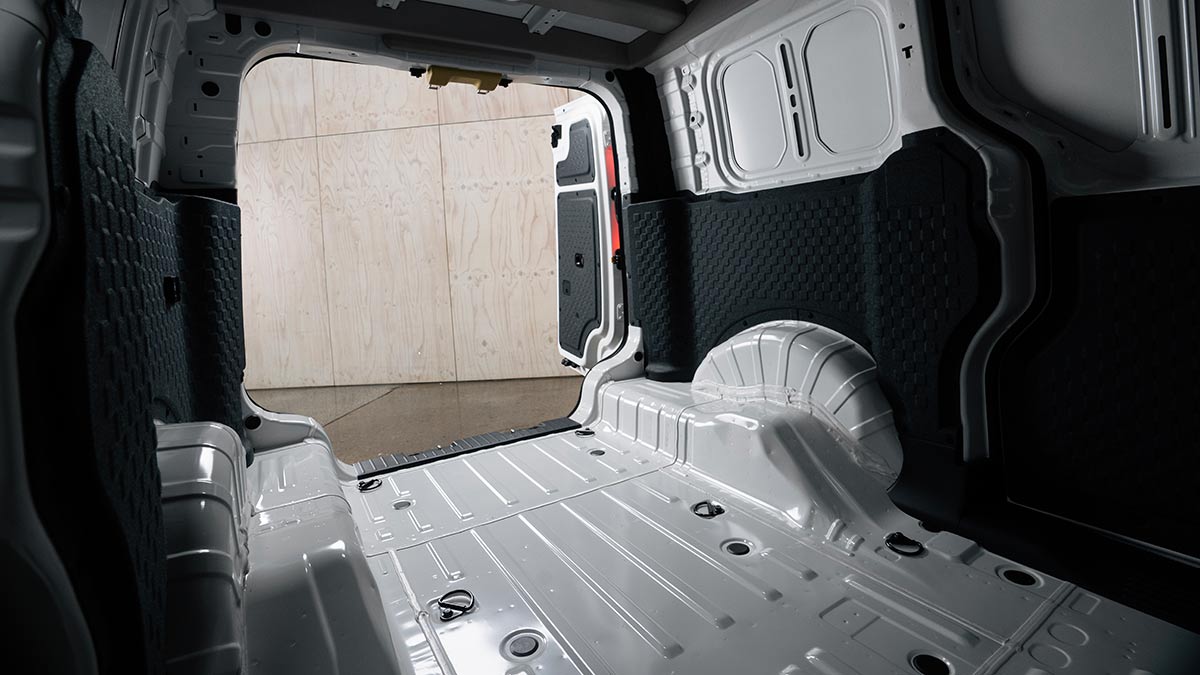 Load area of Kia PV5 Cargo electric van with dark trim on side panels and rear bar doors.