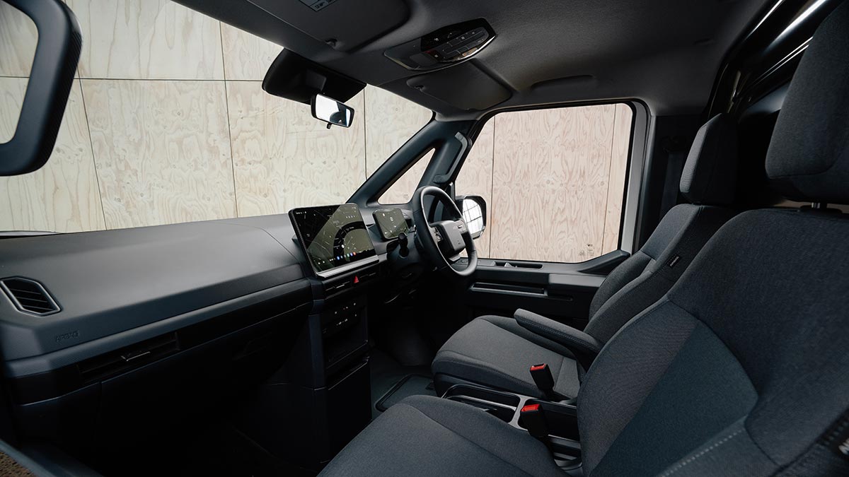 View from front passenger seat of Kia PV5 Cargo van two-seater cabin with twin bucket seats and upright dash with dual digital screens.