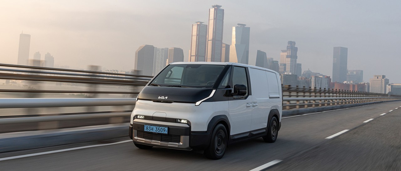 Kia PV5 van against rendered background of city.